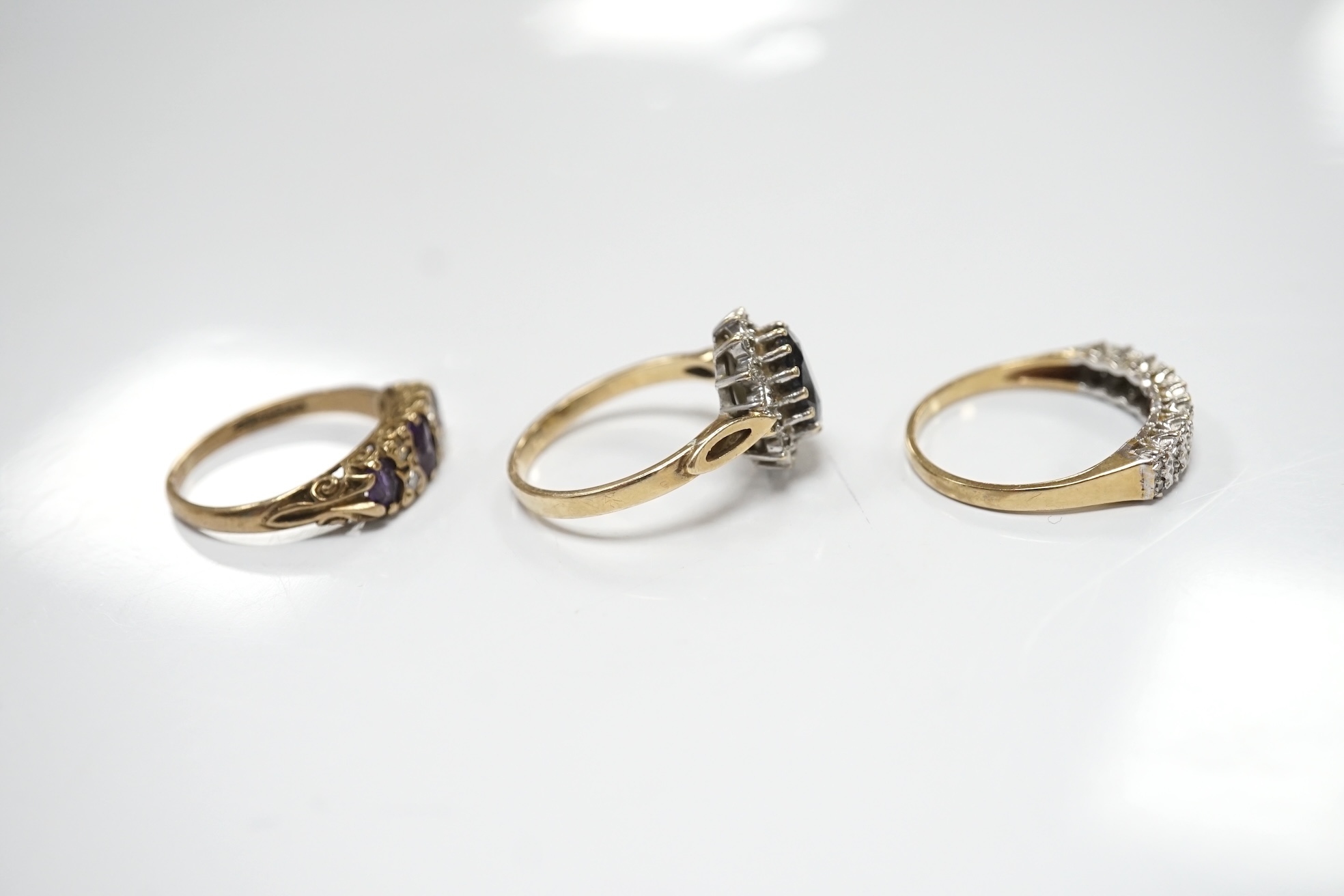 Three assorted 9ct and gem set rings including a diamond chip cluster half hoop and two pairs of yellow metal and gem set ear studs including sapphire? and diamond cluster. Condition - fair to good